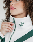 A woman wearing a white sweatshirt with pink and green geometric patterns and a quarter-zip design.