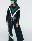 A person wearing a black sweatshirt with green and white details, including a quarter-zip design and chevron patterns, paired with a matching hat.