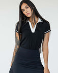 A woman wearing a black and white Angie Polo golf shirt with a collar, short sleeves, and a skirt.