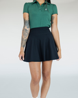 A person wearing a high-waisted black skirt with a green golf shirt. The skirt has side seam pockets and is made of a ribbed fabric.