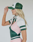 A woman wearing a pink and green Betty Polo shirt with chevron print and a preppy collar, paired with a light pink skirt.
