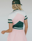 A woman wearing a pink and green Betty Polo shirt with chevron print and a preppy collar, paired with a light pink skirt.