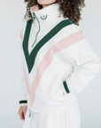 A woman wearing a white sweatshirt with pink and green geometric patterns and a quarter-zip design.