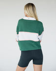 A woman wearing a long sleeve polo shirt with green, white, and pink colors, featuring the text 'Golfing Optional' on the front.