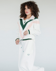 A woman wearing a white sweatshirt with pink and green geometric patterns and a quarter-zip design.