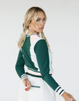 A female model wearing a green and white color-blocked crew neck golf shirt with long sleeves.