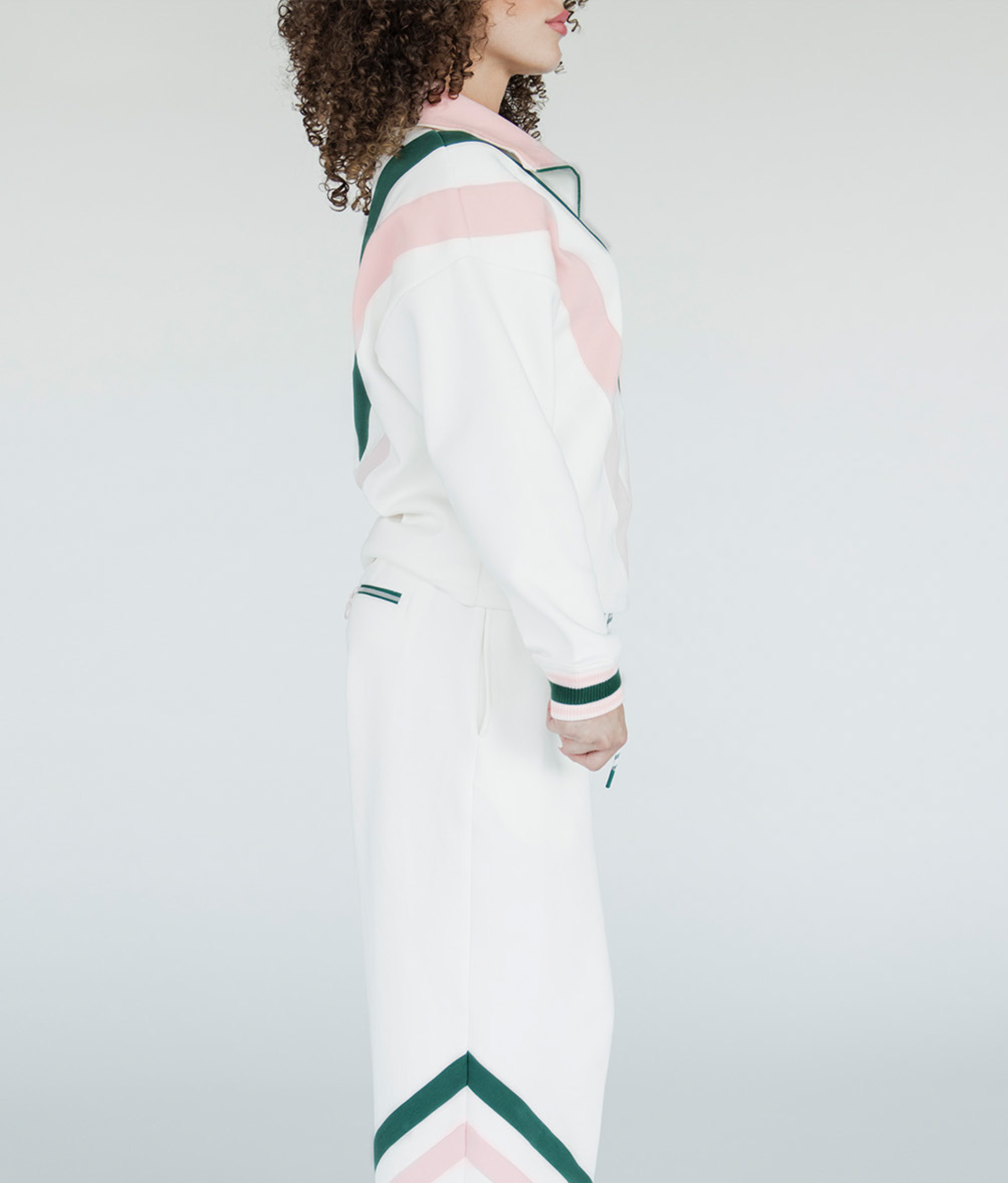 A woman wearing a white sweatshirt with pink and green geometric patterns and a quarter-zip design.