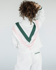 A woman wearing a white sweatshirt with pink and green geometric patterns and a quarter-zip design.