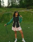 A female model wearing a black rain jacket with green sleeves, featuring a high neck, water-resistant properties, and a double zipper closure.