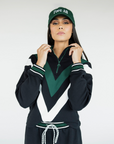 A person wearing a black sweatshirt with green and white details, including a quarter-zip design and chevron patterns, paired with a matching hat.