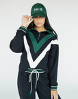A person wearing a black sweatshirt with green and white details, including a quarter-zip design and chevron patterns, paired with a matching hat.