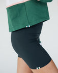 A woman wearing a long sleeve polo shirt with green, white, and pink colors, featuring the text 'Golfing Optional' on the front.