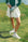 A woman wearing a white pleated golf skirt with a dark color waistband, paired with a green top and pink sneakers.
