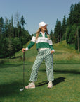 A woman wearing a long sleeve polo shirt with green, white, and pink colors, featuring the text 'Golfing Optional' on the front.
