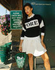 Person wearing a black and white sweater with 'FORE' printed on it
