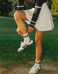 A woman wearing a white high-waisted skirt with built-in shorties and side seam pockets, paired with a black top.