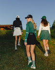 Three girls in skirts and long sleeve quarter zips with coordinating hats.