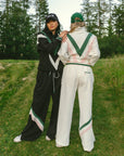 Two models wearing black and white sweatpant with green and pink and green stripe details, paired with a matching sweatshirt.