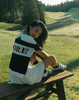 Person wearing a black and white sweater with 'FORE' printed on it on a golf course