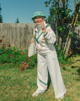 Person wearing a white top and white pants with green and pink accents.