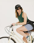 A pair of blue and white geometric shorts, knee-length, worn by a model paired with a green top and white sneakers.