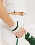 A woman wearing a white sleeveless tank top with a built-in bra, suitable for golfing, paired with white shorts and a visor.