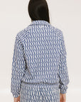 A woman wearing a long sleeve golf jacket with a pattern of blues and whites.