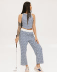 A person standing wearing the Bronson Pant in indigo color, which features a geometric pattern. The pants are casual and the person is paired them with a matching top and pink sneakers.