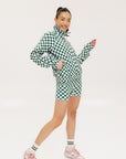 A person wearing green and white checkered biddy shorties and a matching checkered golf jacket, standing against a white background.