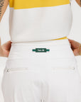A person wearing white athletic pants and a white t-shirt with yellow details, standing against a white background.
