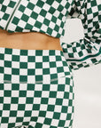 A person wearing green and white checkered biddy shorties and a matching checkered golf jacket, standing against a white background.