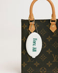 Louis Vuitton handbag with a white 'Fore All' golf ball holder attached