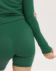 A pair of green mid-rise shorts with a logo on the left leg, worn with a matching green crop top.
