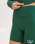 A pair of green mid-rise shorts with a logo on the left leg, worn with a matching green crop top.