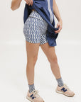 A pair of blue and white geometric shorts, knee-length, worn by a model paired with an indigo Erin Dress.