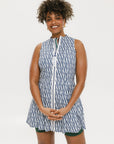 A model wearing a sleeveless blue and white geometric patterned dress with a zipper at the top, suitable for golf.