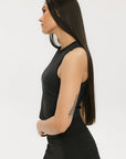 A smiling woman wearing a black tank top with a built-in bra, posing against a white background.
