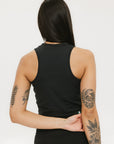A smiling woman wearing a black tank top with a built-in bra, posing against a white background.