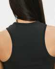 A smiling woman wearing a black tank top with a built-in bra, posing against a white background.