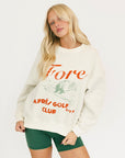 Woman wearing a white sweatshirt with red text and green shorts on a white background