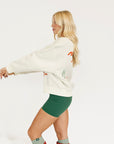 Woman wearing a white sweatshirt with red text and green shorts on a white background
