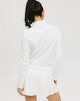 A woman wearing a white long sleeve golf top with a mock neckline.