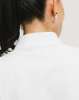 A woman wearing a white long sleeve golf top with a mock neckline.