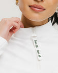 A woman wearing a white long sleeve golf top with a mock neckline.