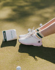 A person wearing retro ankle socks in mustard and green colors, paired with a white shoe.