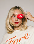 Person holding a red 'Cola Bum' product over one eye against a plain background