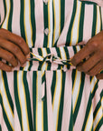 Close-up of a person adjusting a striped shirt with green, pink, and yellow vertical stripes.