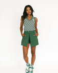 Person wearing a green skort and checkered top on a white background