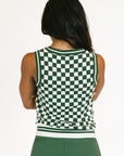 Person wearing a green and white checkered sleeveless top with green pants on a white background