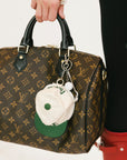 Louis Vuitton handbag with a unique keychain held by a person wearing red boots.